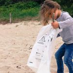 une petite fille collecte des déchets sur une plage en Bretagne